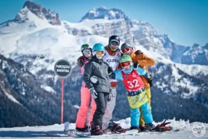 Grupa ludzi w strojach narciarskich na tle gór we Włoszech.