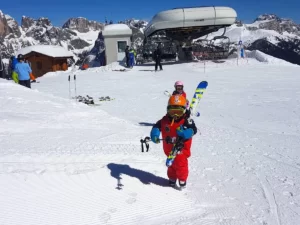 Małe dziecko w stroju narciarskim na tle wyciągu.