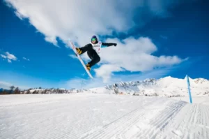 Mężczyzna wyskakujący na snowboardzie na tle gór we Wloszech.
