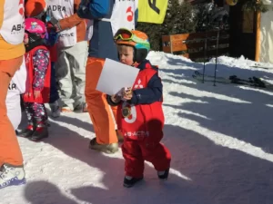 Dziecko w stroju narciarskim z dyplomem.